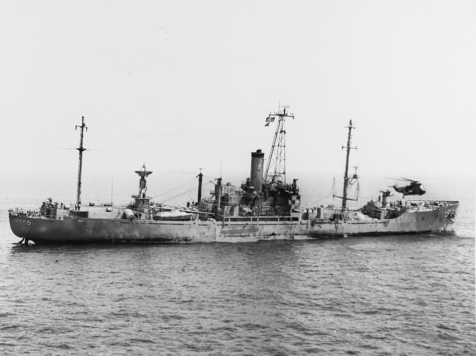 The USS Liberty, June 8, 1967 — A U.S. Navy Sea King helicopter hovers over the damaged USS Liberty (AGTR-5) following the Israeli attack that killed 34 American sailors and wounded 171 more. The ship had been flying American flags and was under aerial surveillance for six hours before the two-hour assault. NSA documents related to the incident remain classified nearly 60 years later. Photo: U.S. Navy / Wikimedia Commons